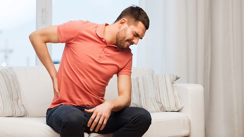 unhappy man suffering from backache at home