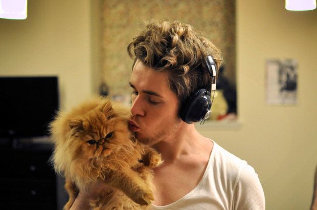 Man wearing headphones holding with cat