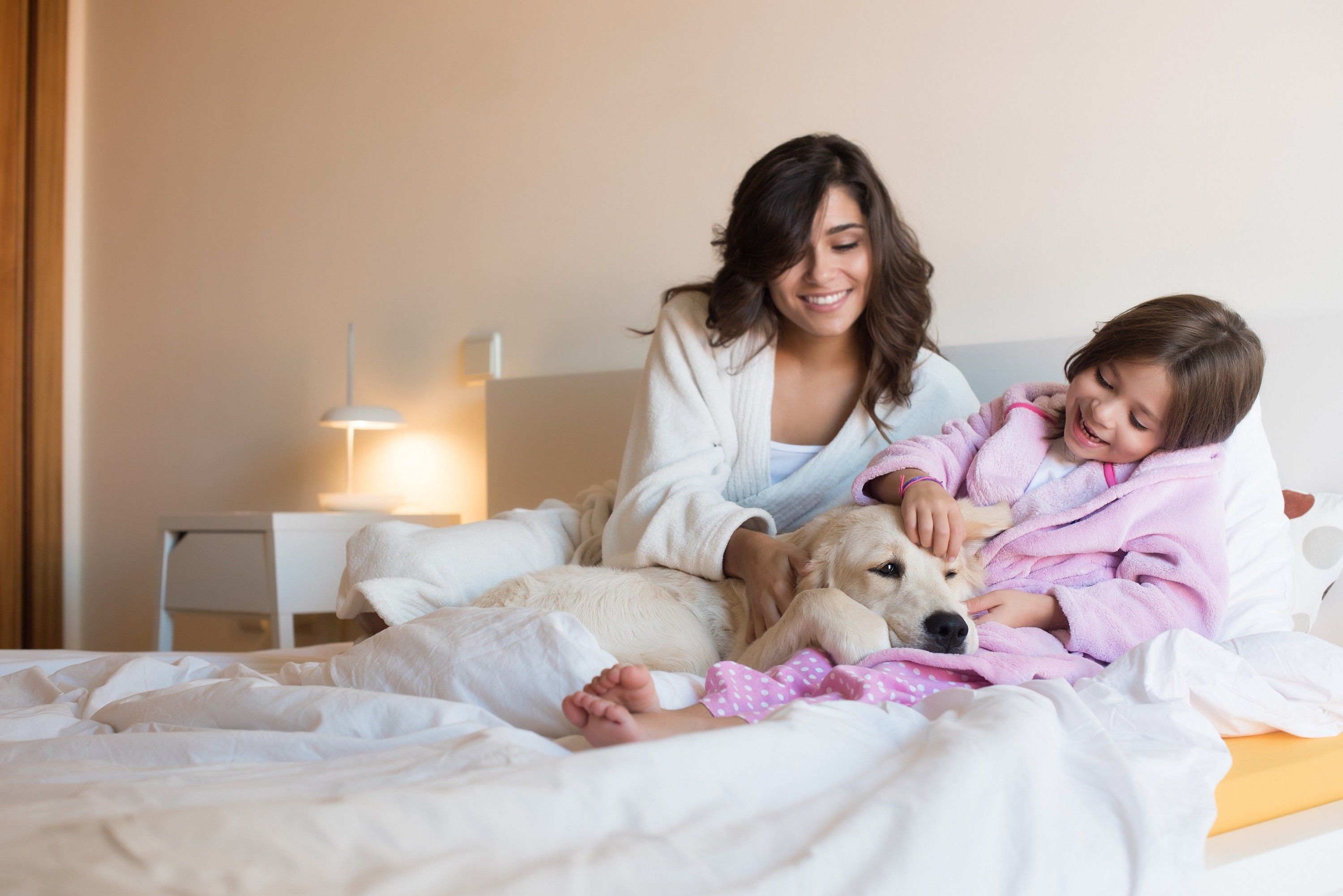 Mother and daughter with dog in bed